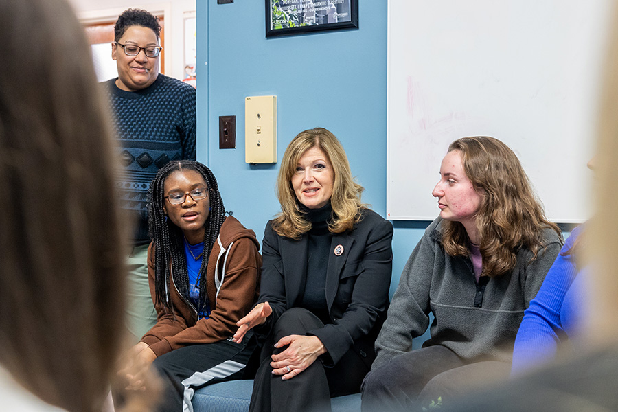 A professor meets with students and staff members.