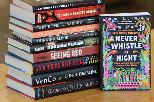 A copy of the book Never Whistle at Night next to a stack of other Native American literature publications.